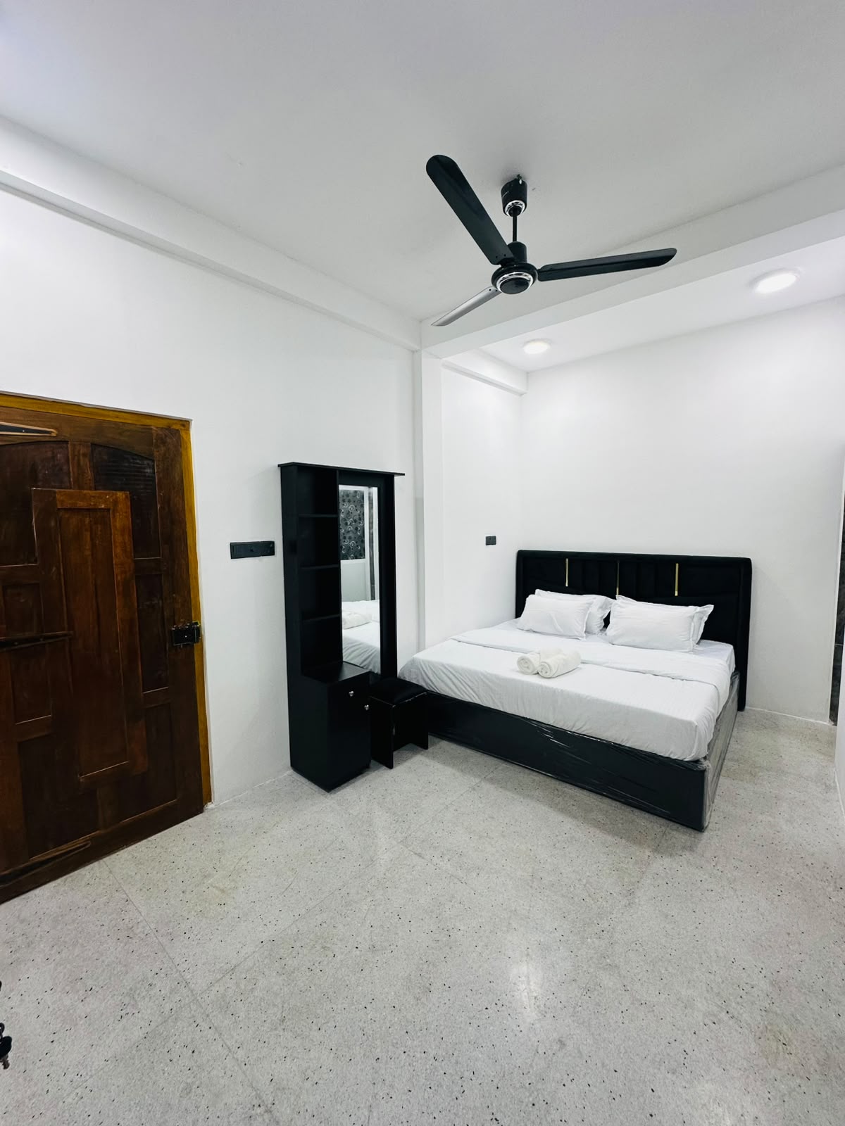 Bedroom with framed headboard and neutral tile flooring